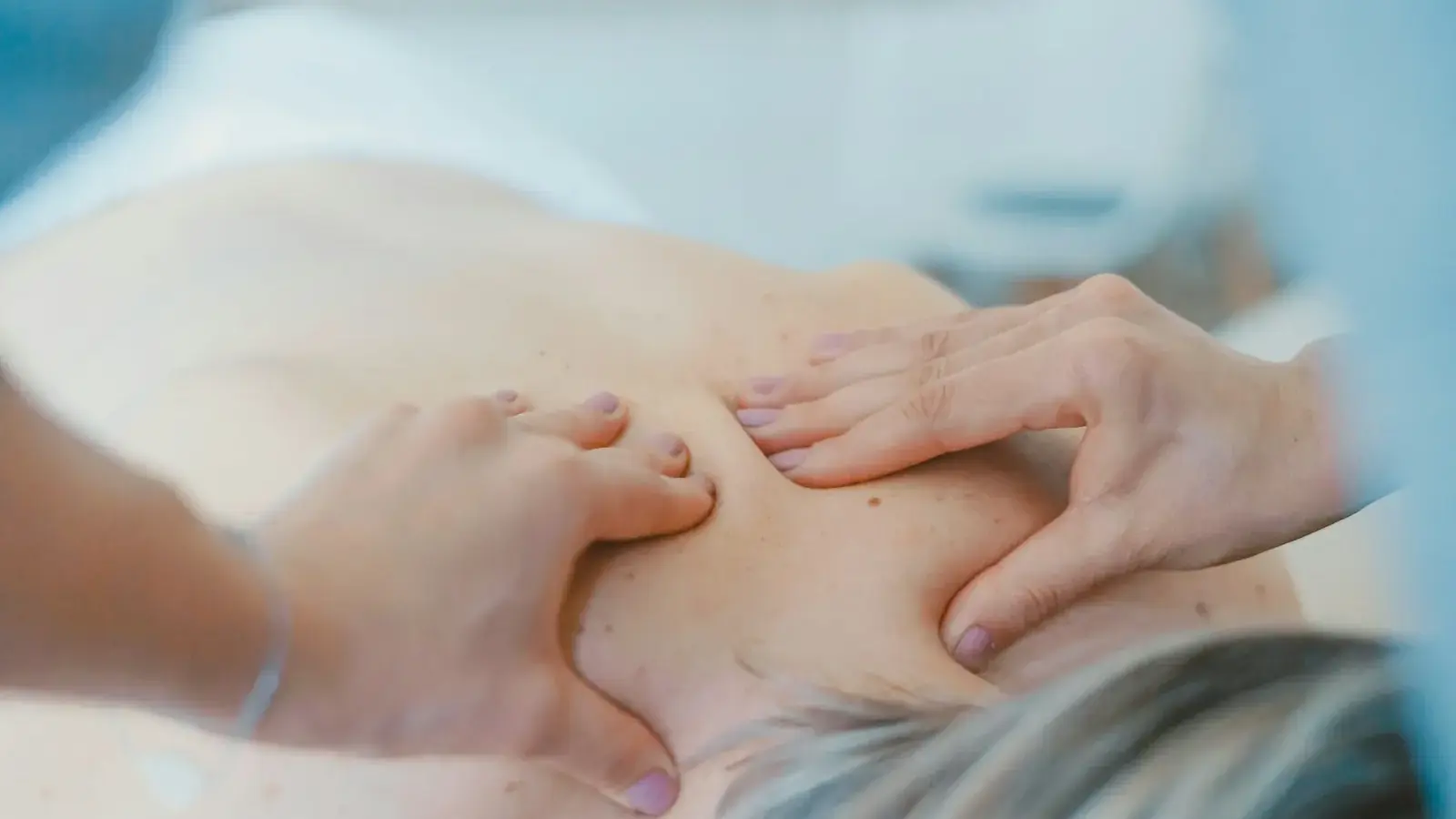 Massage therapist working on a patient's upper back and shoulders