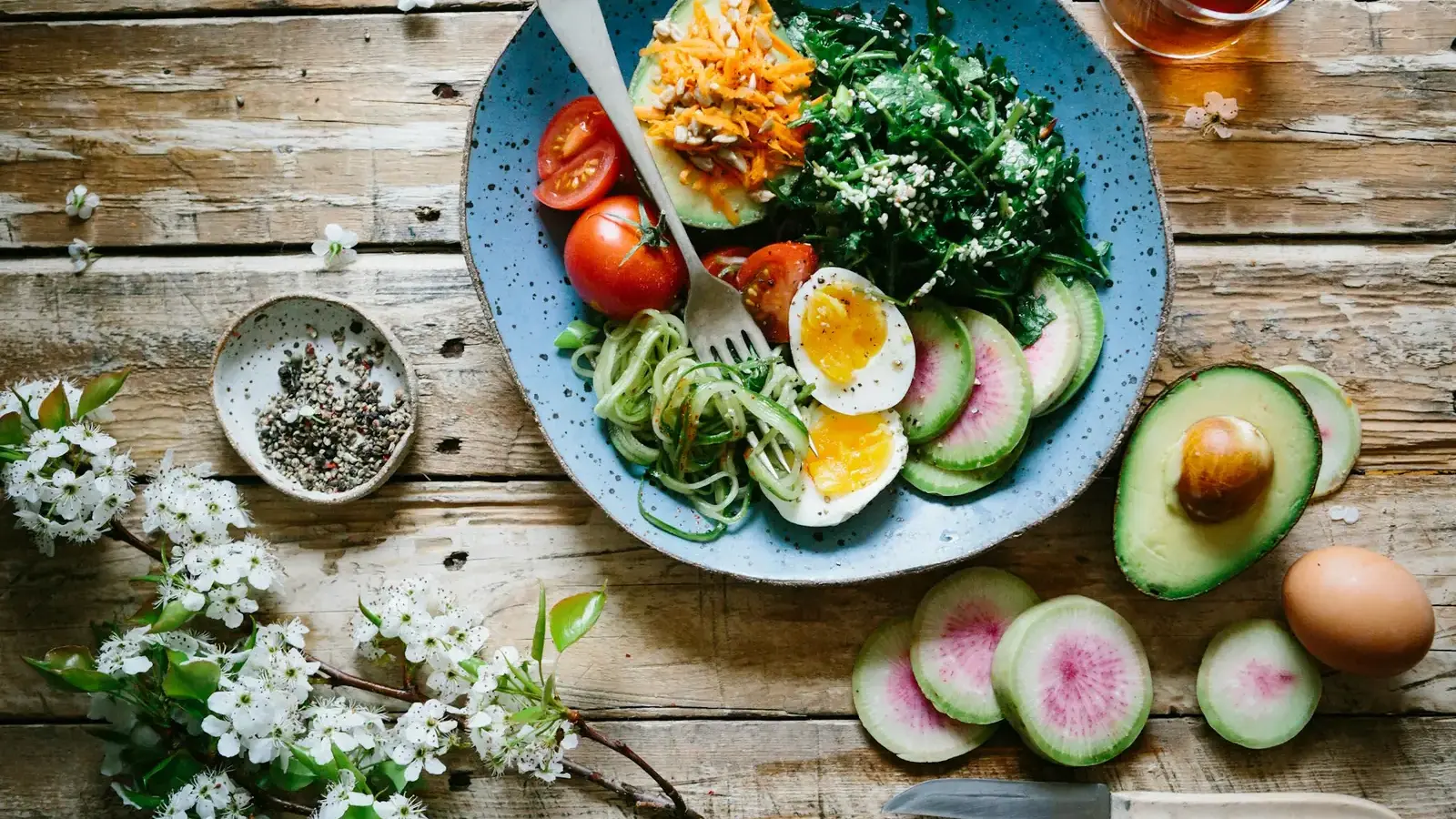 Balanced plate of vegetables, eggs and avocado on a wooden table
