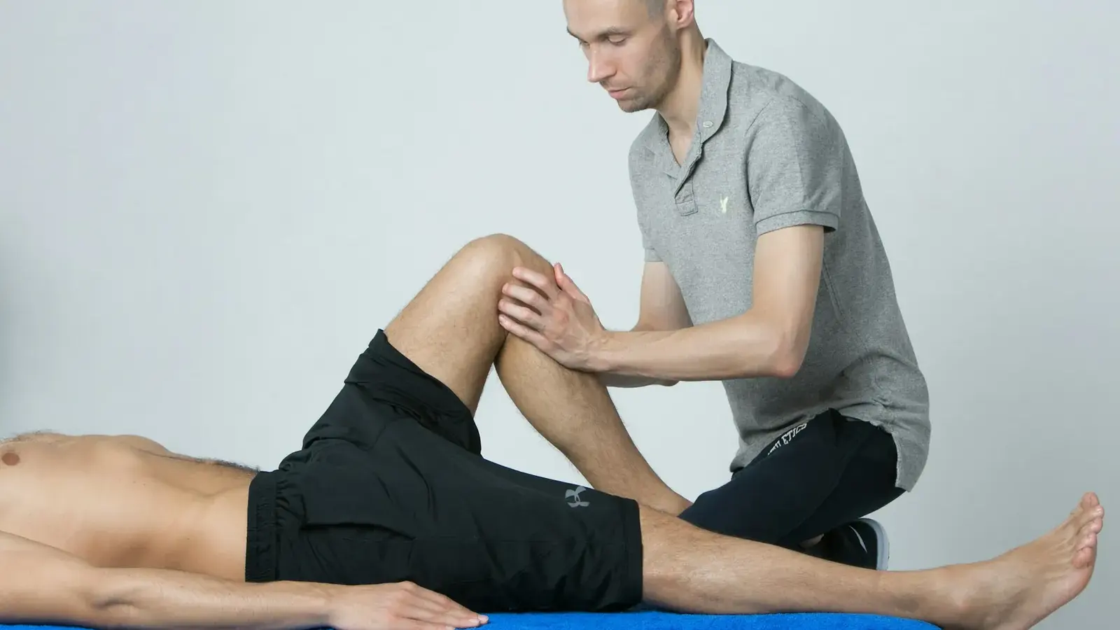Physiotherapist assessing a patient's knee on a treatment table