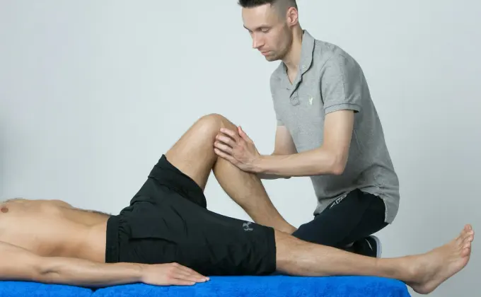 Physiotherapist assessing a patient's knee on a treatment table