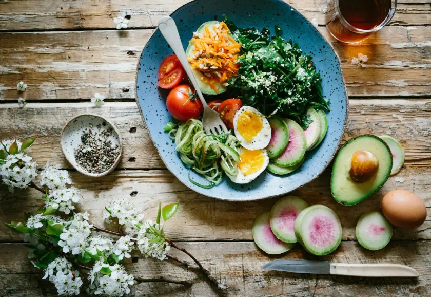 Balanced plate of vegetables, eggs and avocado on a wooden table