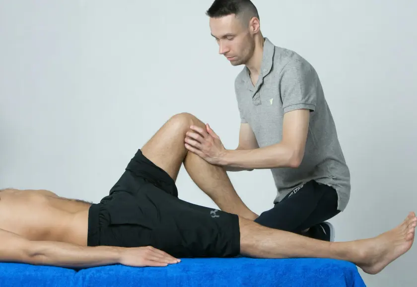 Physiotherapist assessing a patient's knee on a treatment table